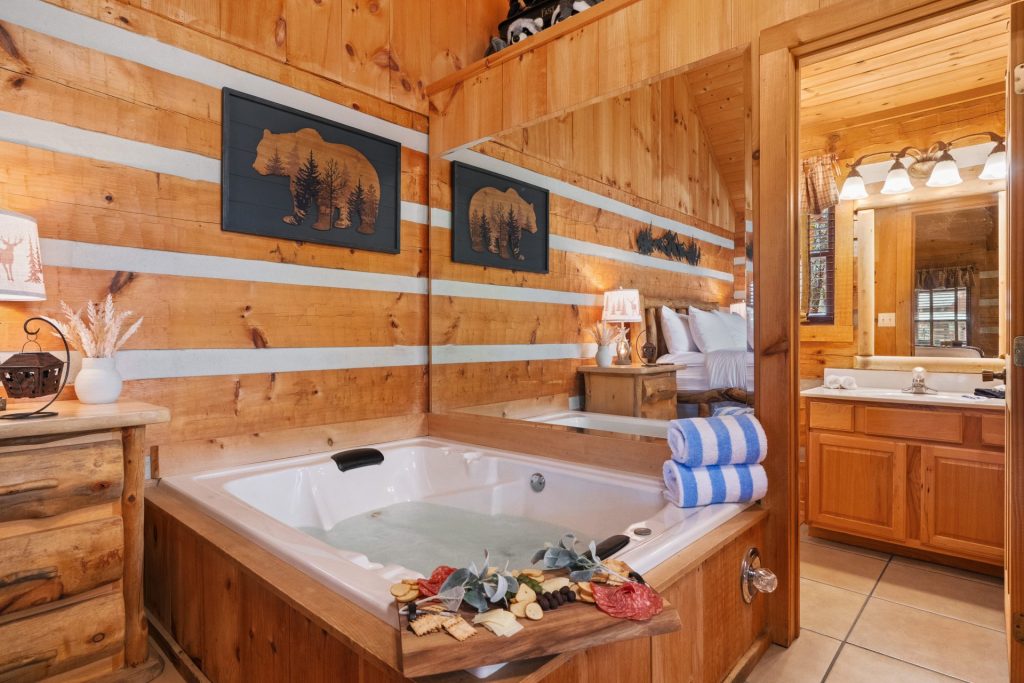 Romantic bedroom suite at Nestled Oaks cabin in Sevierville TN with indoor jetted tub, rustic décor, and wood finishes.