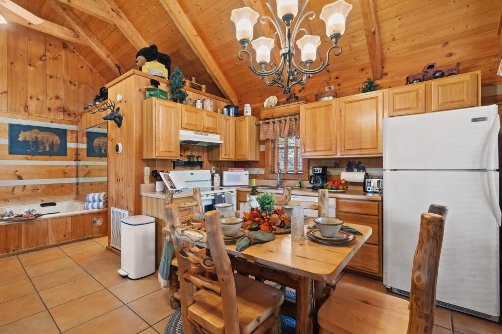 Kitchen and dining area at Nestled Oaks cabin in Sevierville TN with log furniture, chandelier, and indoor jetted tub.