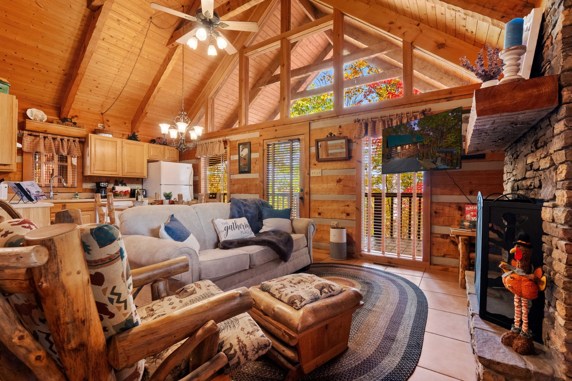 Cozy living room at Nestled Oaks cabin in Sevierville TN with vaulted ceilings, large windows, and stone fireplace.