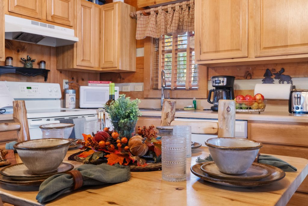 Kitchen at Nestled Oaks cabin in Sevierville TN with wooden cabinets, dining table set, and modern appliances.