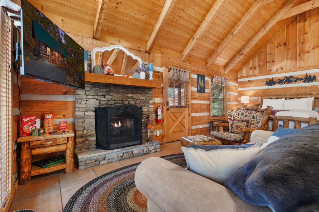 Living area at Nestled Oaks cabin in Sevierville TN featuring stone fireplace, log furniture, and cozy mountain décor.