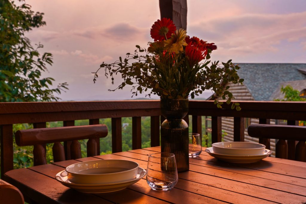 Deck dining area with sunset and flowers at Dancing Embers cabin